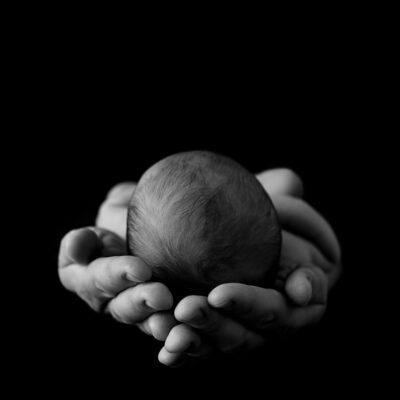 Newborn baby photography photoshoot. Cute baby held in black and white. Photographer of photo shoot is Cheryl Catton , Woking.