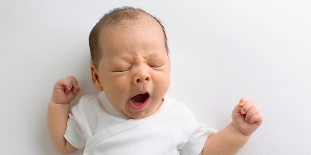 Newborn baby boy yawning during newborn photoshoot in Woking