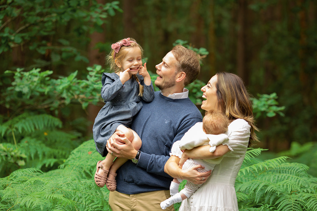 Little girl pulling a funny face at her mum and dad on a family photoshoot in Woking and her parents laughing