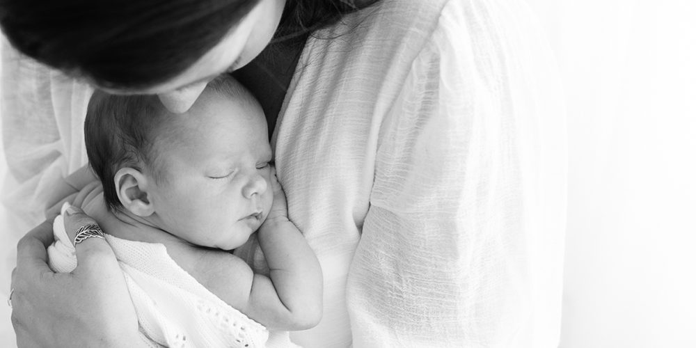 Mum cuddling sleeping baby during newborn photoshoot in Woking