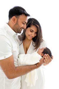 Woking baby photographer. New parents looking at their baby girl during newborn photoshoot in Woking