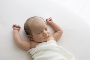 Baby girl sleeping with her arms above her head during a Woking newborn photoshoot